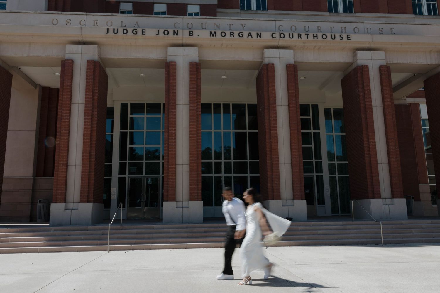 Couple in wedding attire share a kiss outside Judge Jon R. Morgan Courthouse on their wedding day.