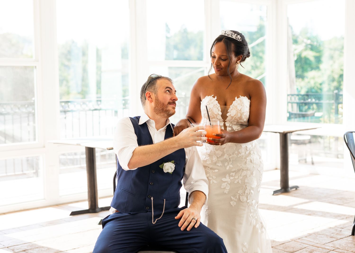 Black and white wedding photo of newlyweds sharing a joyful candid moment together with bokeh lights in background.
