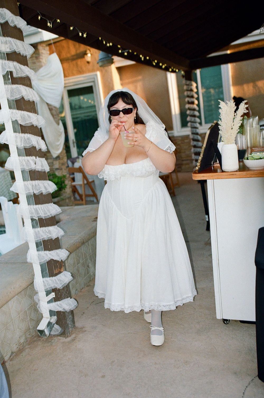 Bride drinks signature cocktail at her backyard wedding reception near Old Brown House in Highland Park.