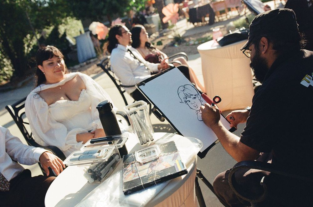 Film photo of wedding reception featuring a caricature artist and lively dance party.