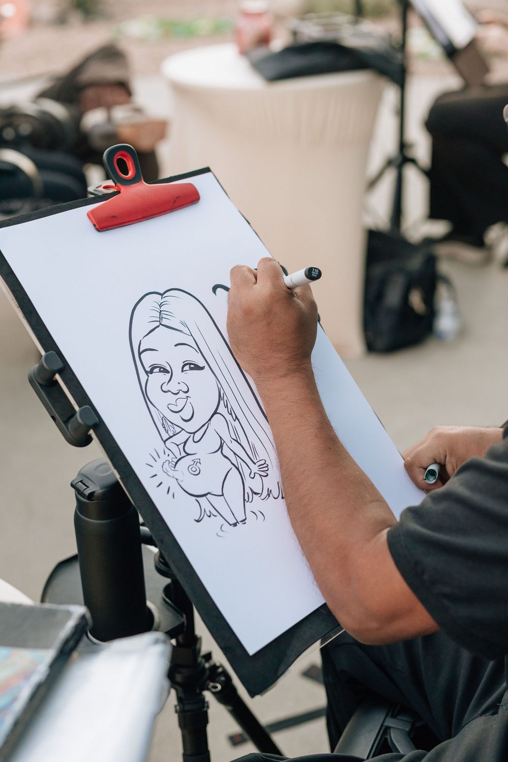 Caricature artist draws pregnant wedding guest at wedding reception in Los Angeles.