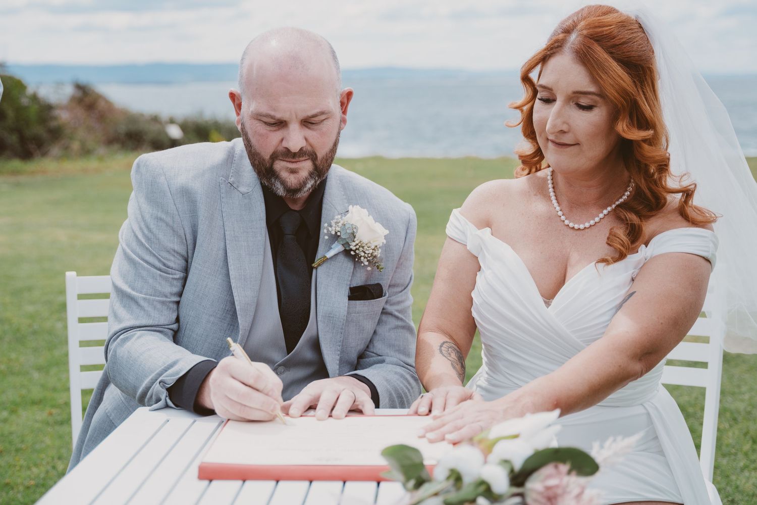 Groom signs the marriage certificate beside his bride - legal paperwork at a small NSW elopement