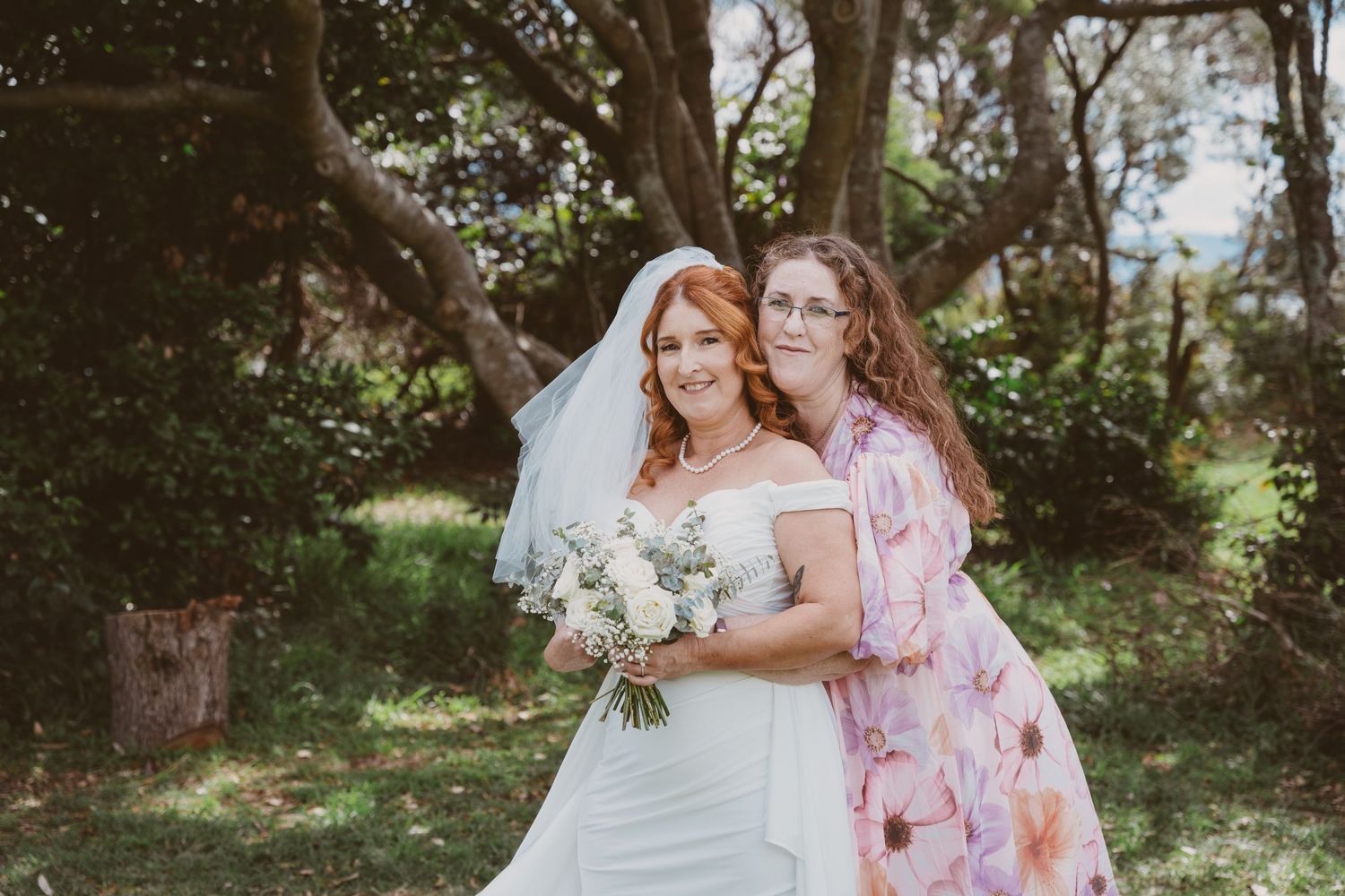 Bride with bouquet poses with a guest under twisted coastal trees - intimate elopement guest photos