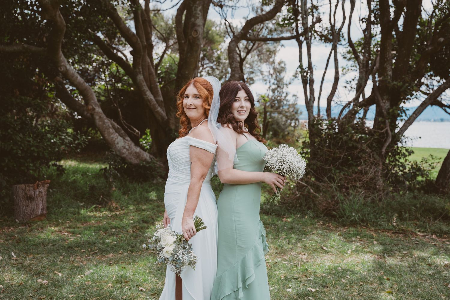 Bride and her bridesmaid in sage green under coastal trees - relaxed elopement portraits