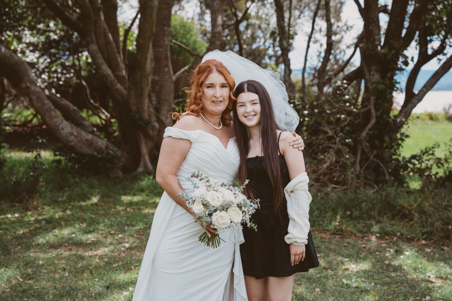 Bride with a young guest in black under the trees - candid family moments at a small elopement