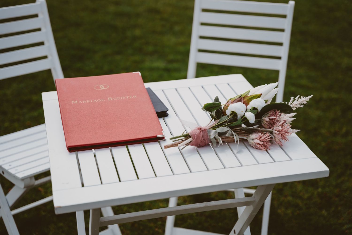 Marriage register and bouquet on a white table set for an intimate outdoor ceremony - small elopement details