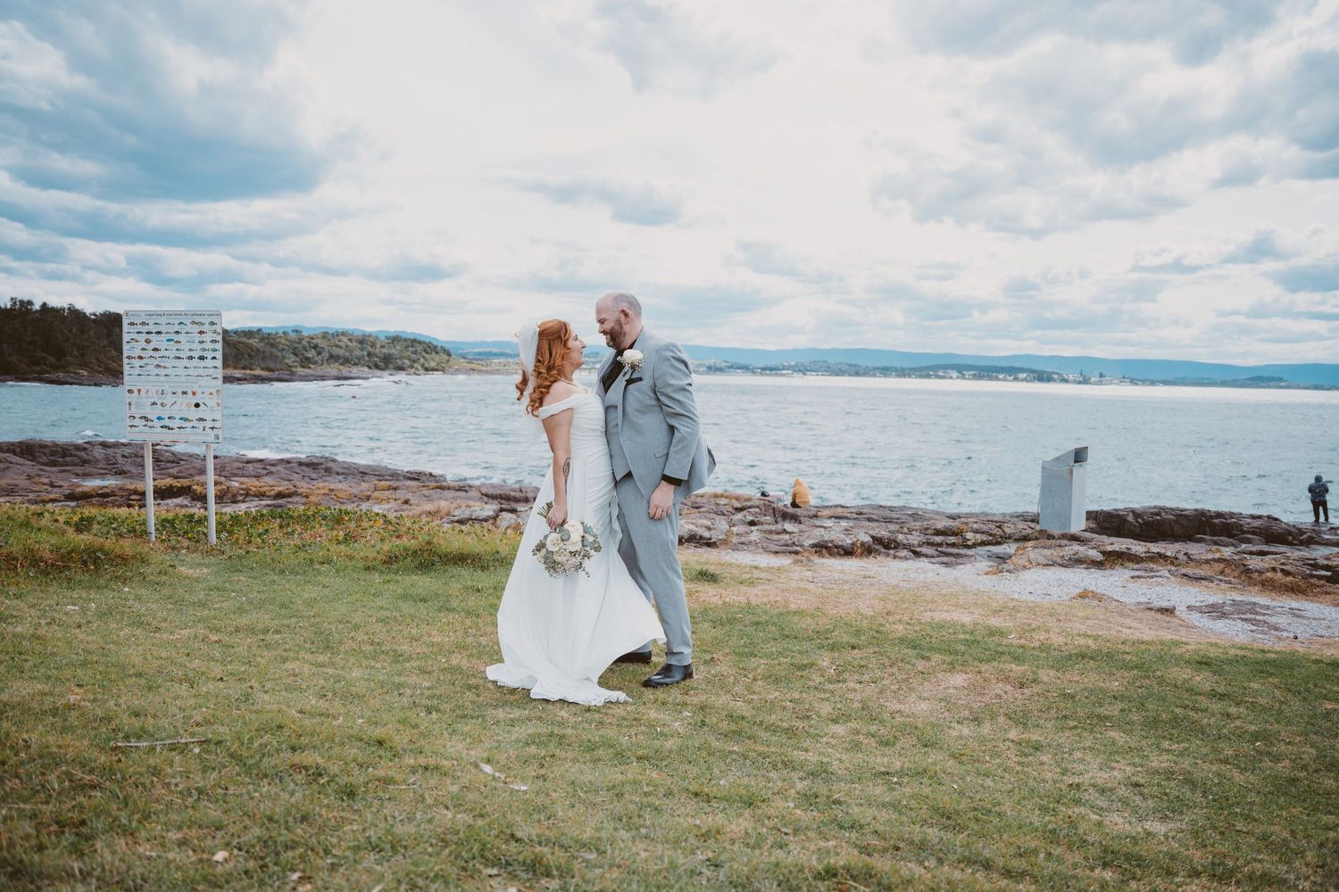 Couple stand on a grassy headland with ocean views - Illawarra-style coastal elopement photography