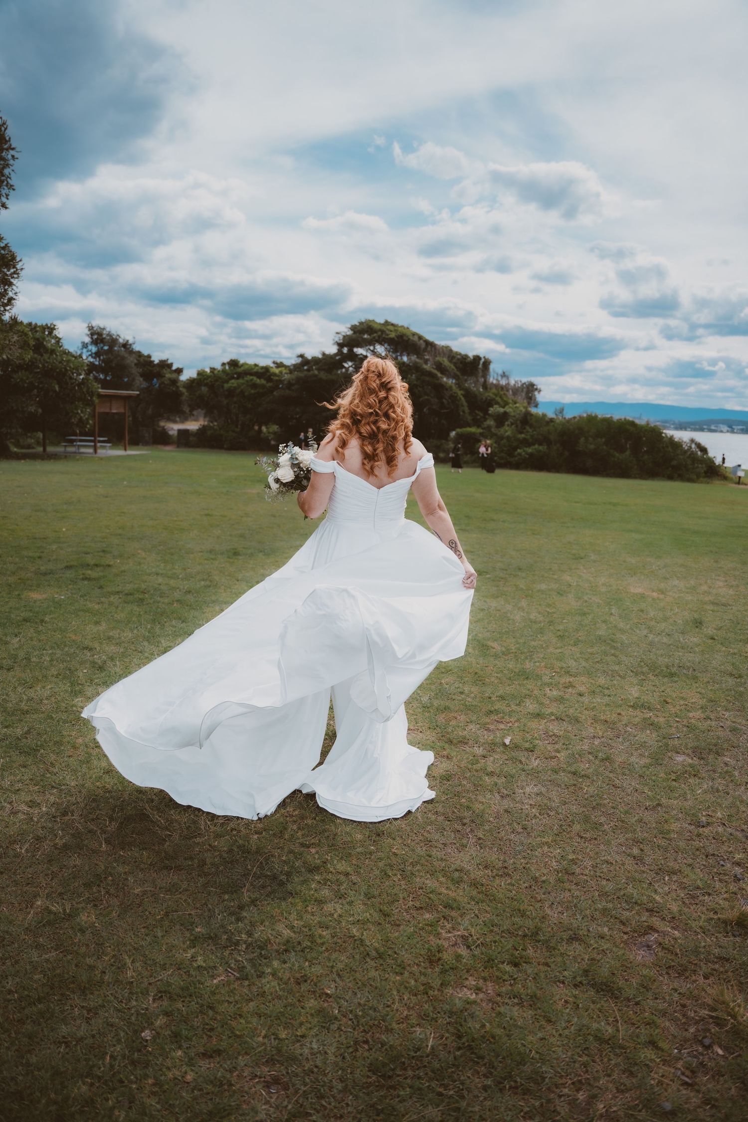 Bride twirls her flowing gown on a seaside lawn - fun, natural elopement photography