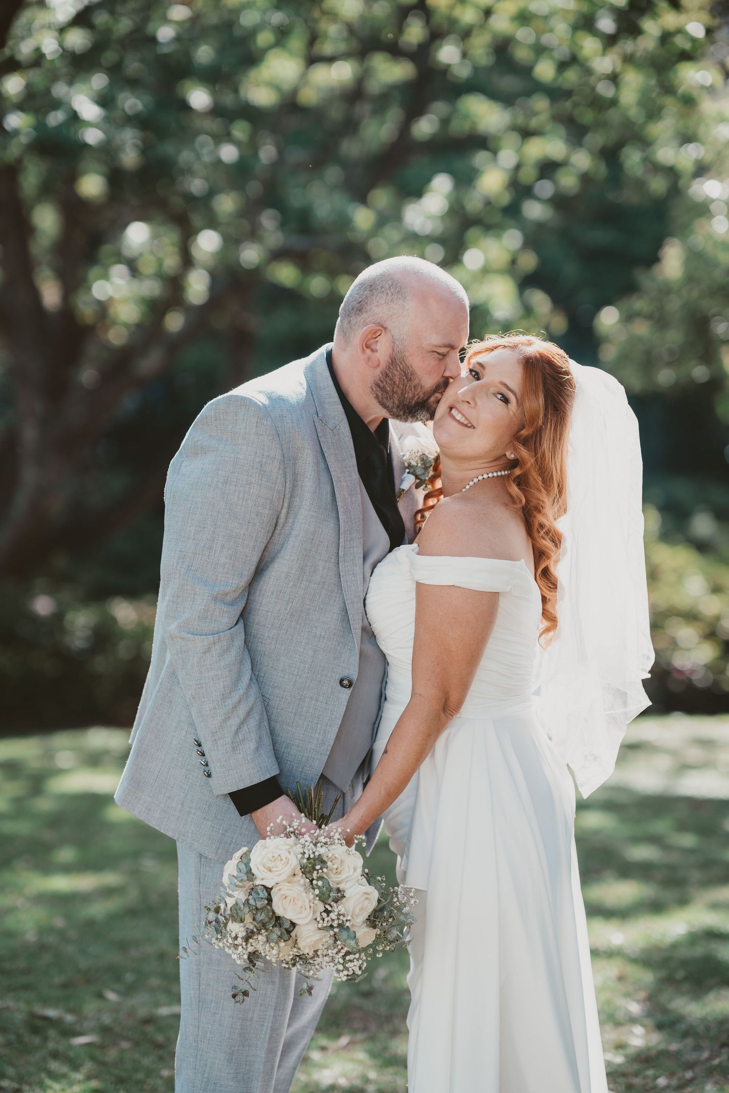 Groom kisses his bride's forehead in the garden - tender moments at an intimate elopement