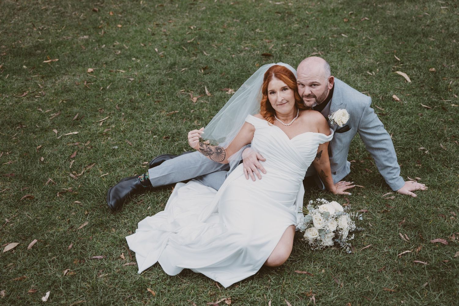 Bride and groom laugh while sitting on the grass - candid, natural elopement photos