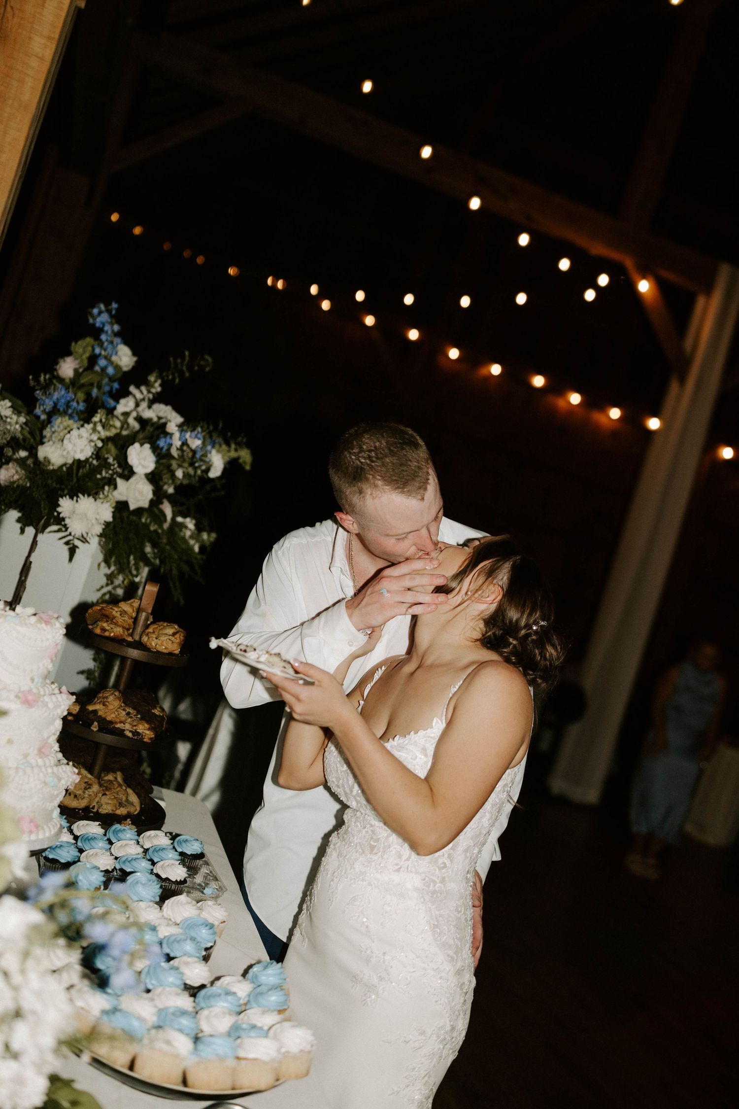 Black and white photo of guests dancing at a wedding reception inside a rustic barn venue.