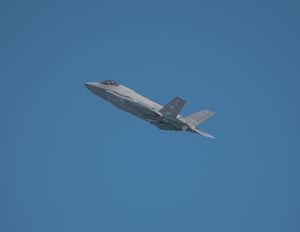 F-35 fighter jet flying against a clear blue sky, showcasing its stealth design and advanced military aviation technology.