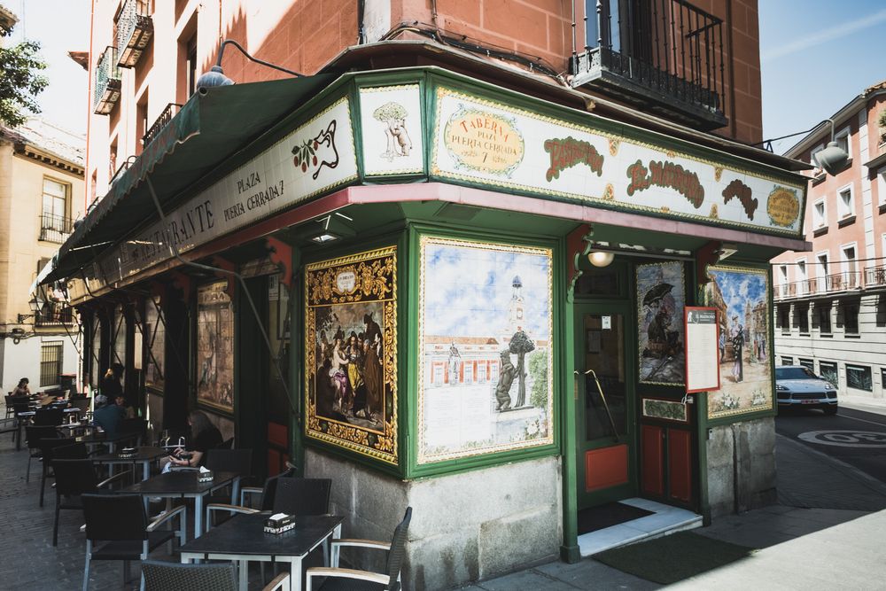 Colorful ornate corner restaurant with decorative tilework and outdoor seating in Madrid, Spain.