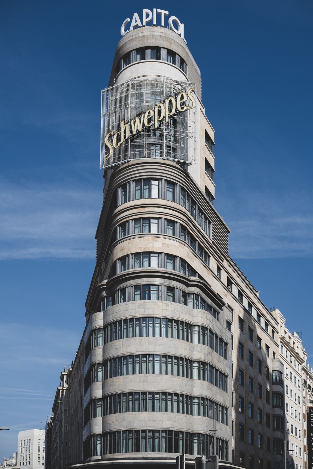 Art Deco Capitol building with Schweppes sign against blue sky in Madrid, Spain.