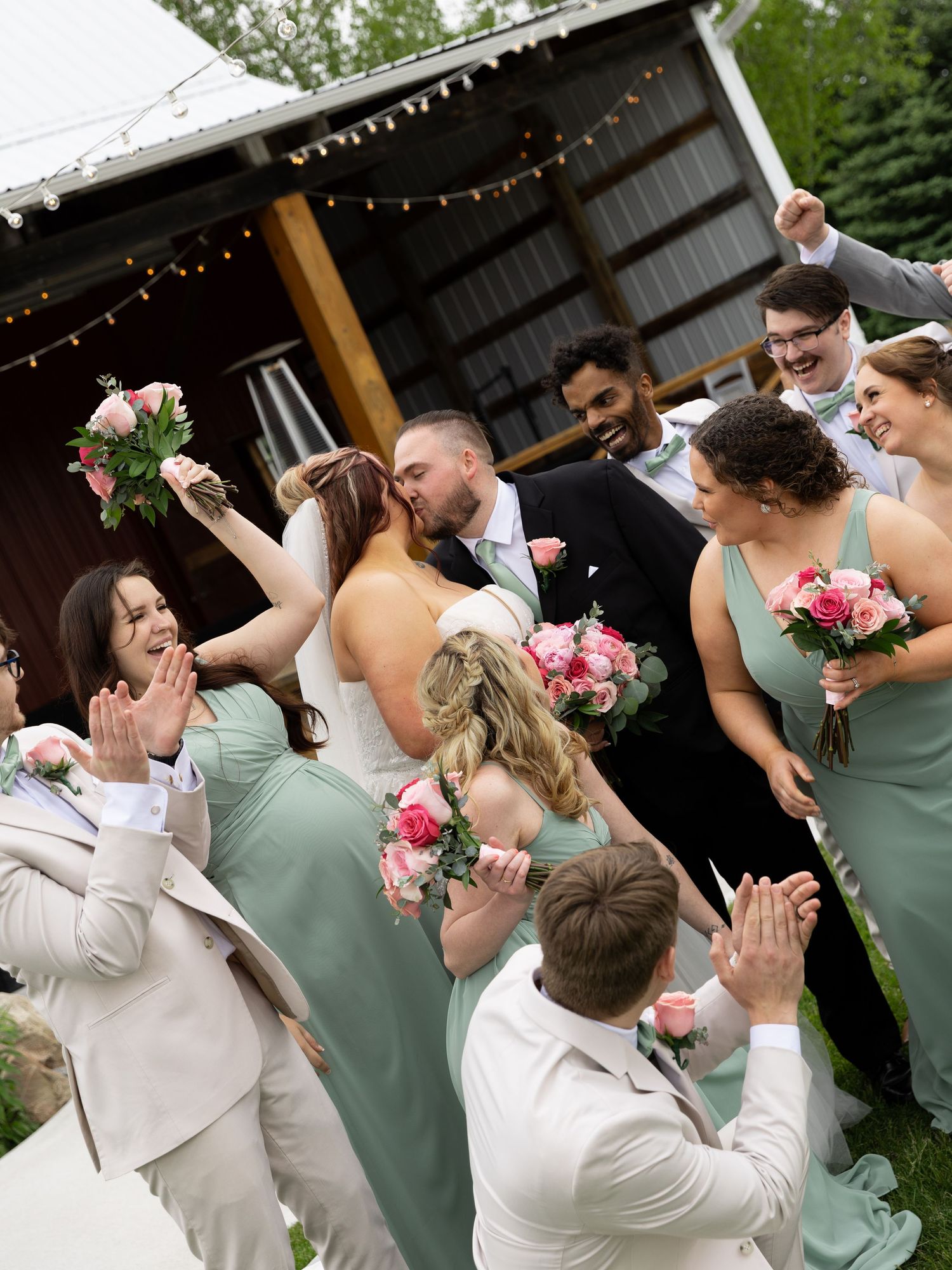 Smiling bride surrounded by pink and white rose bouquets with eucalyptus greenery on her wedding day.