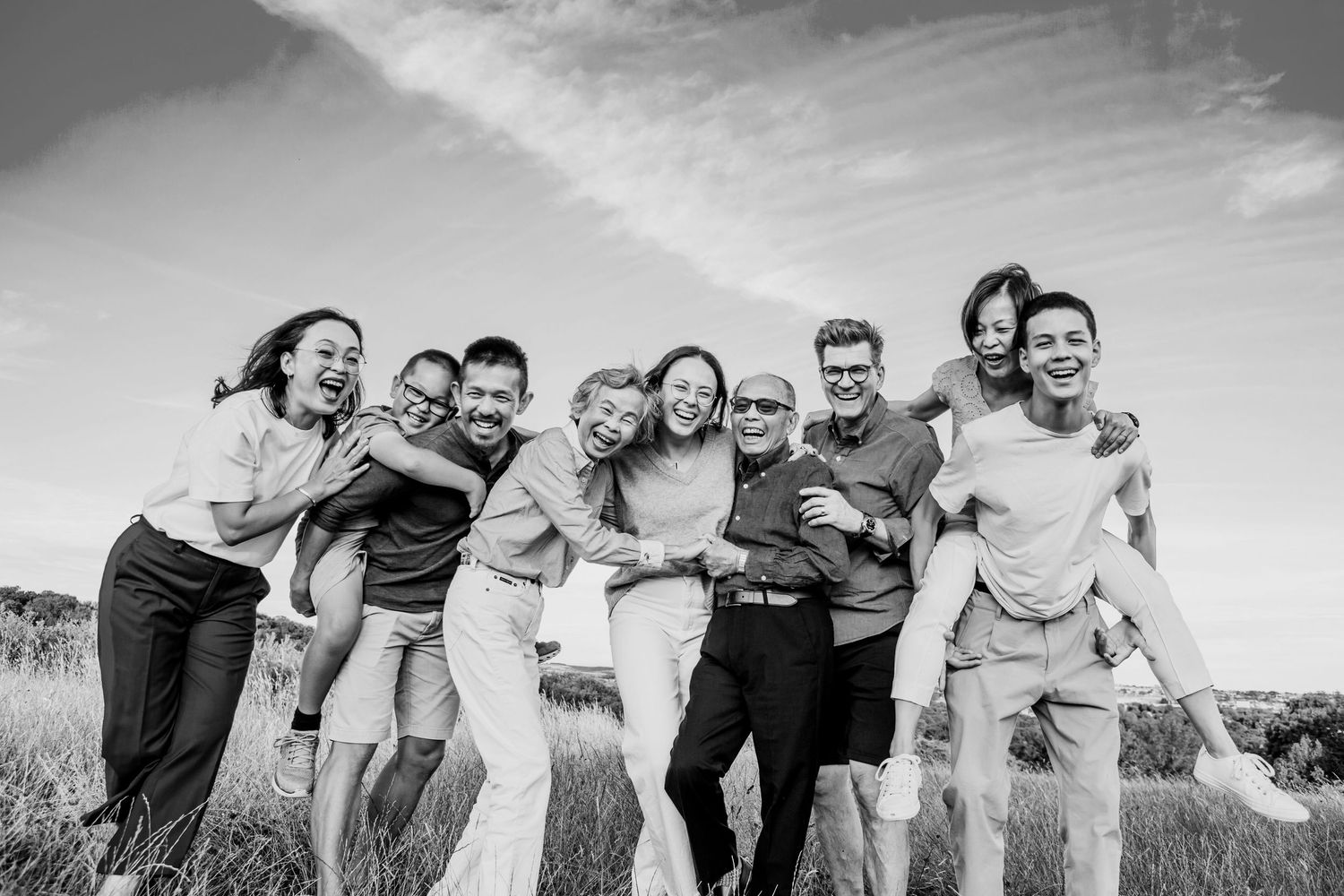 Black and white portrait of three generations of family laughing together during an outdoor family photography session.
