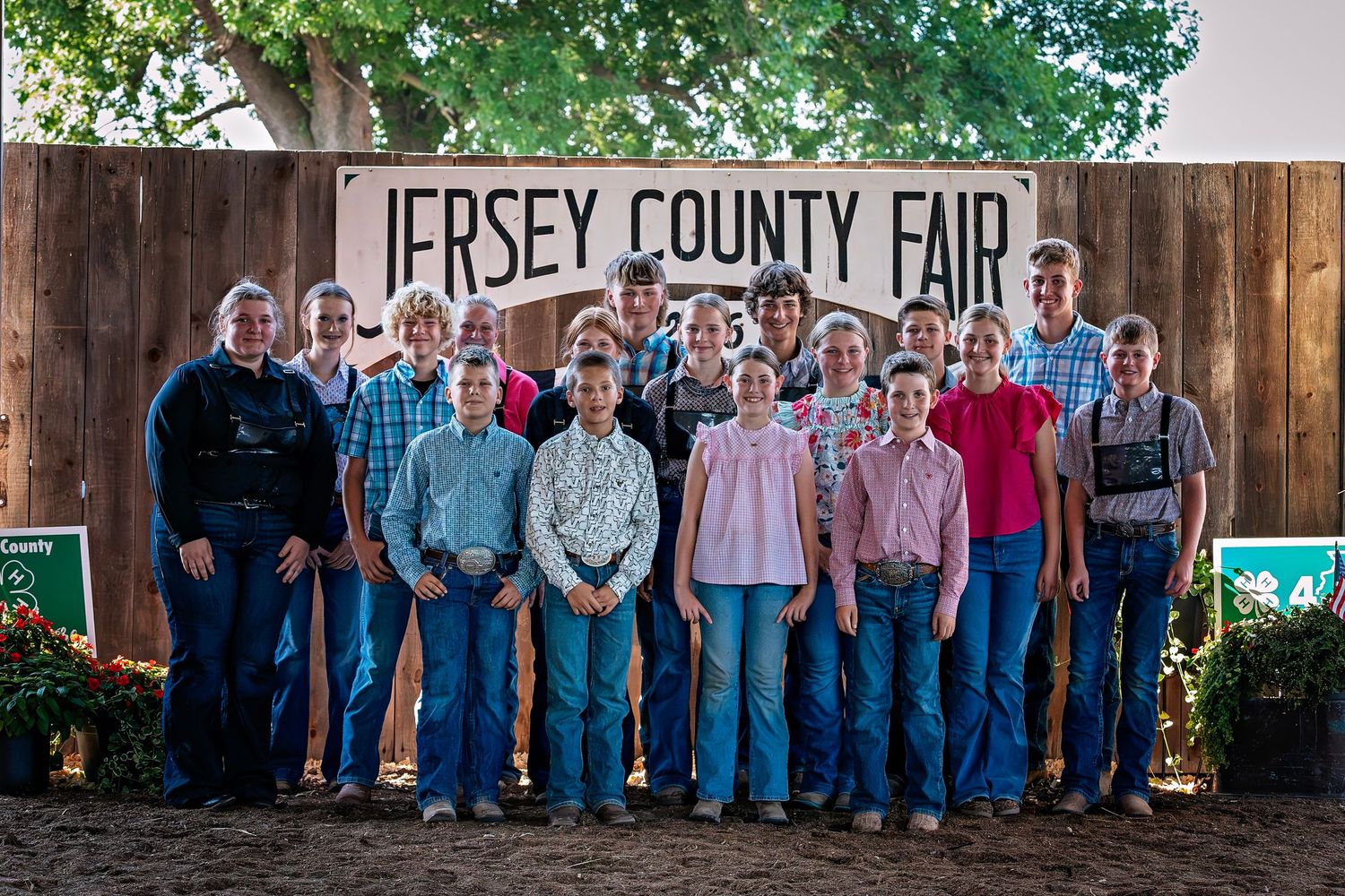 Group of people posing in front of a Jersey County Fair sign outdoors.