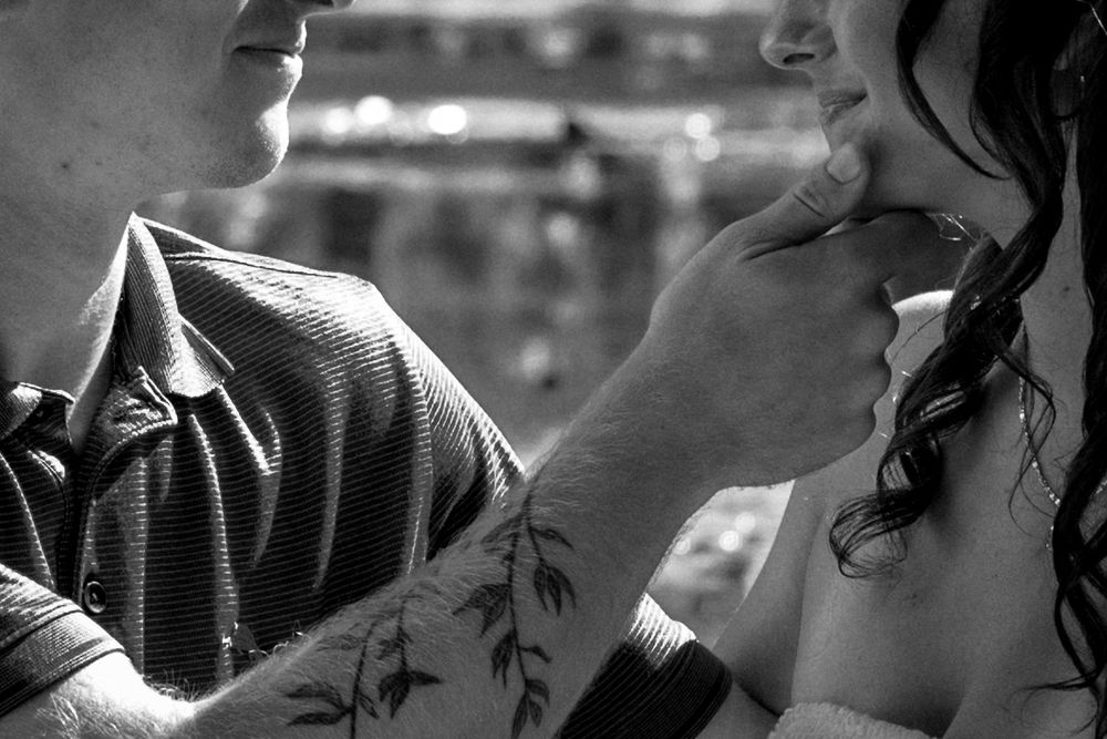 Black and white photo of a couple sharing an intimate moment, man with leaf tattoo on arm touching woman's chin.