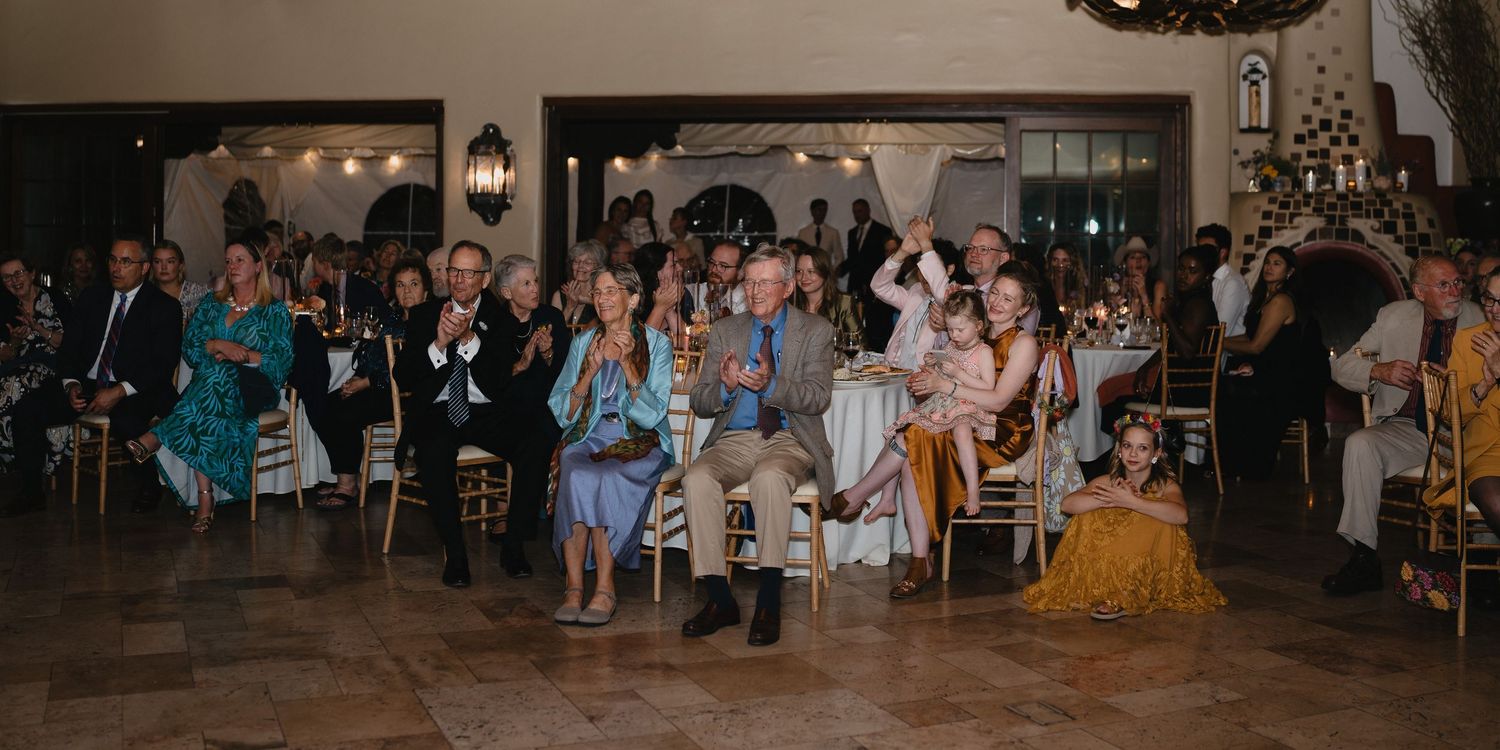 Guests clapping and celebrating at an elegant wedding reception in a beautifully decorated ballroom venue.