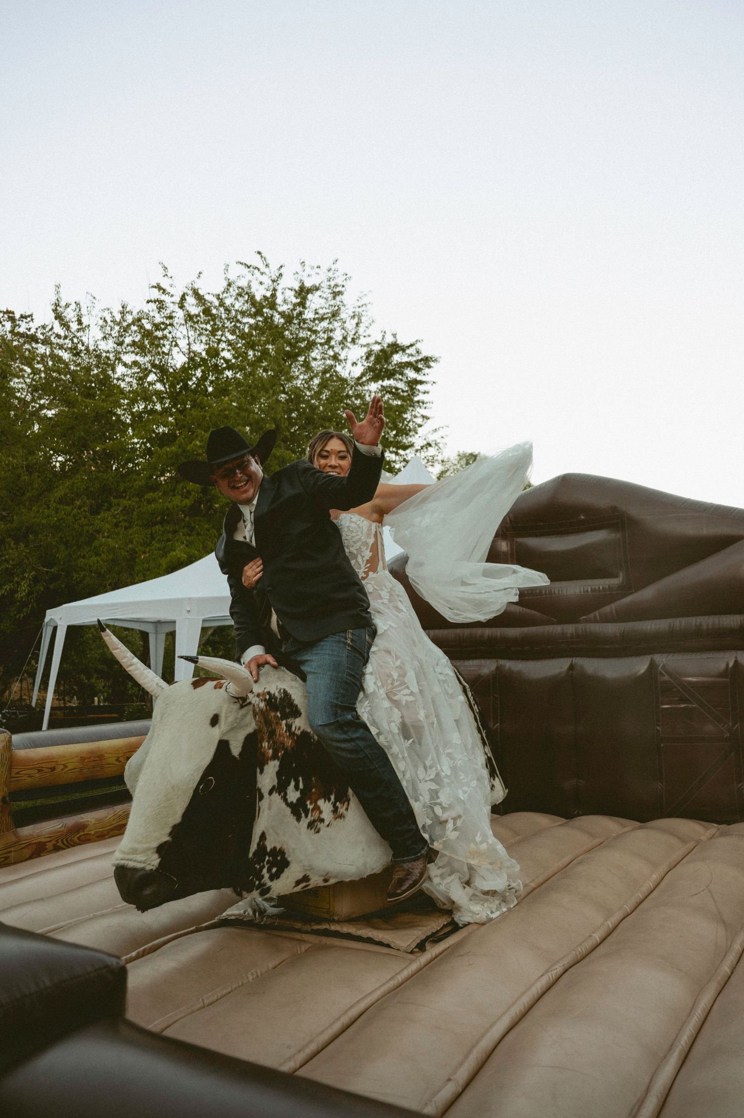 Bride and groom walk a mountain path with snow-capped Grand Teton peaks and lush green trees in the background.