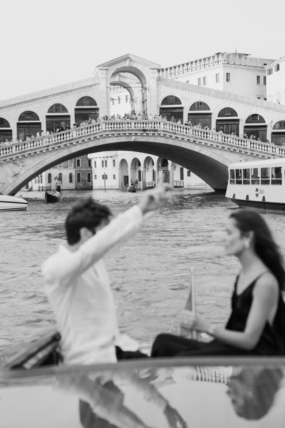 Couple on gondola near Rialto Bridge in Venice, black and white photo.