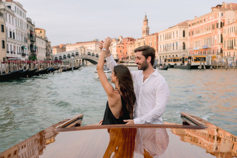 Couple dancing on a gondola on the Grand Canal in Venice, Italy, with the Rialto Bridge in the background.