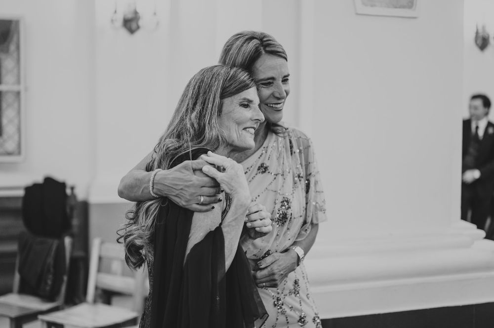 Two women sharing a warm emotional hug in black and white wedding photo.