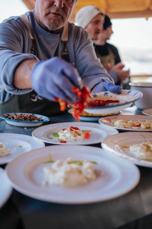 Chef in blue gloves plating colorful dishes with red peppers at an outdoor event.
