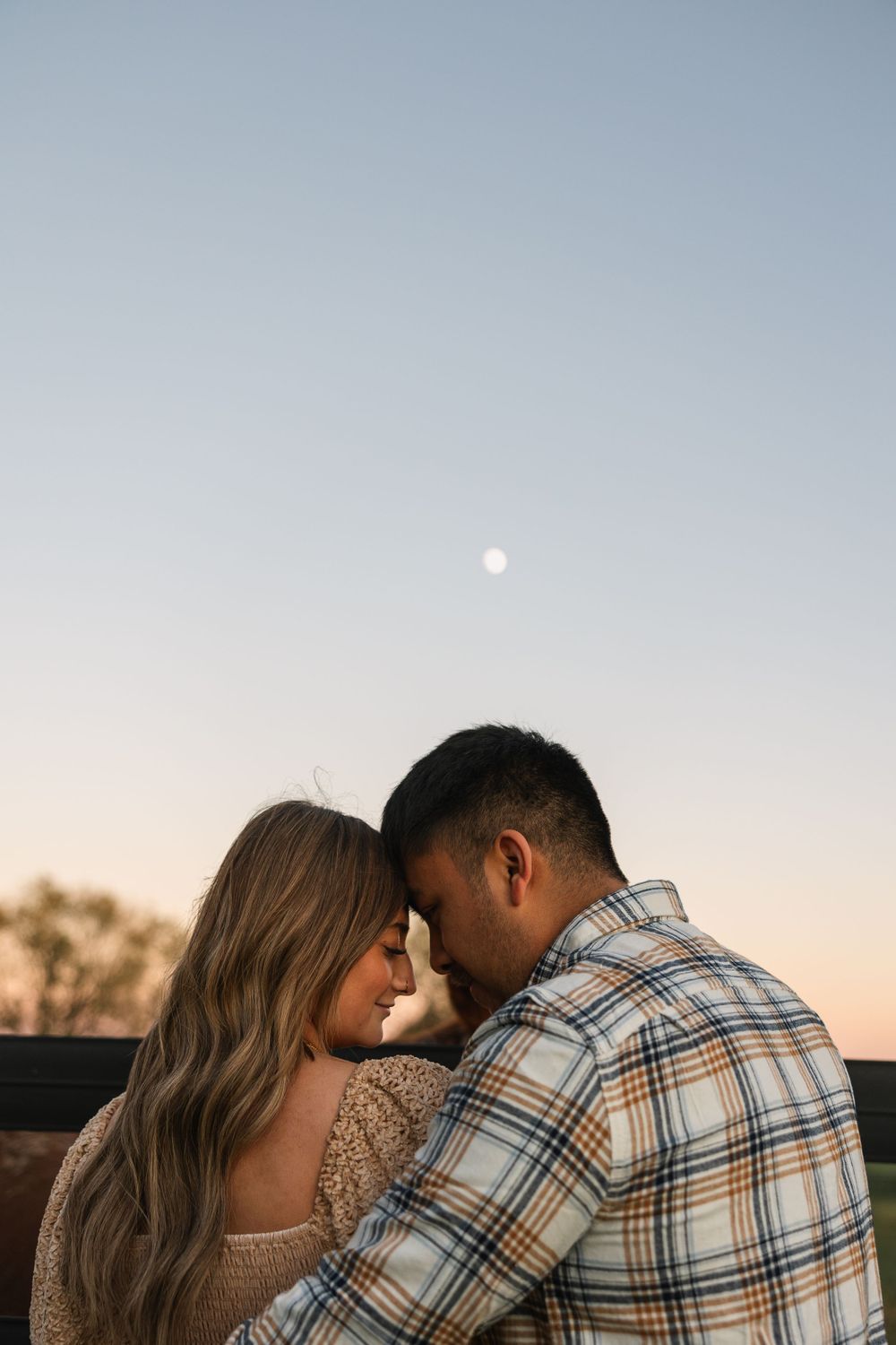 Couple sharing intimate moment at sunset in plaid and knit clothing.