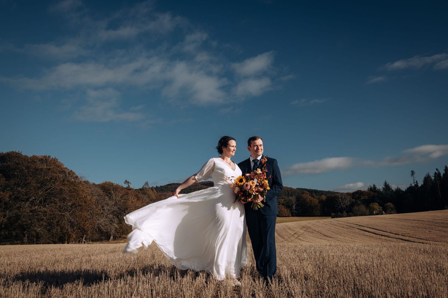 A wedding ceremony under a floral arch with scottish elements including traditional kilts.