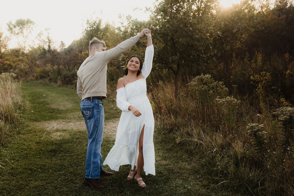 Couple dancing together on nature trail with bride wearing flowing white dress with thigh slit.