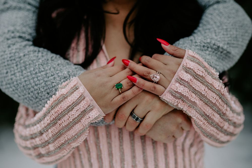 Close-up of hands with red nail polish and engagement rings showing a tender moment.
