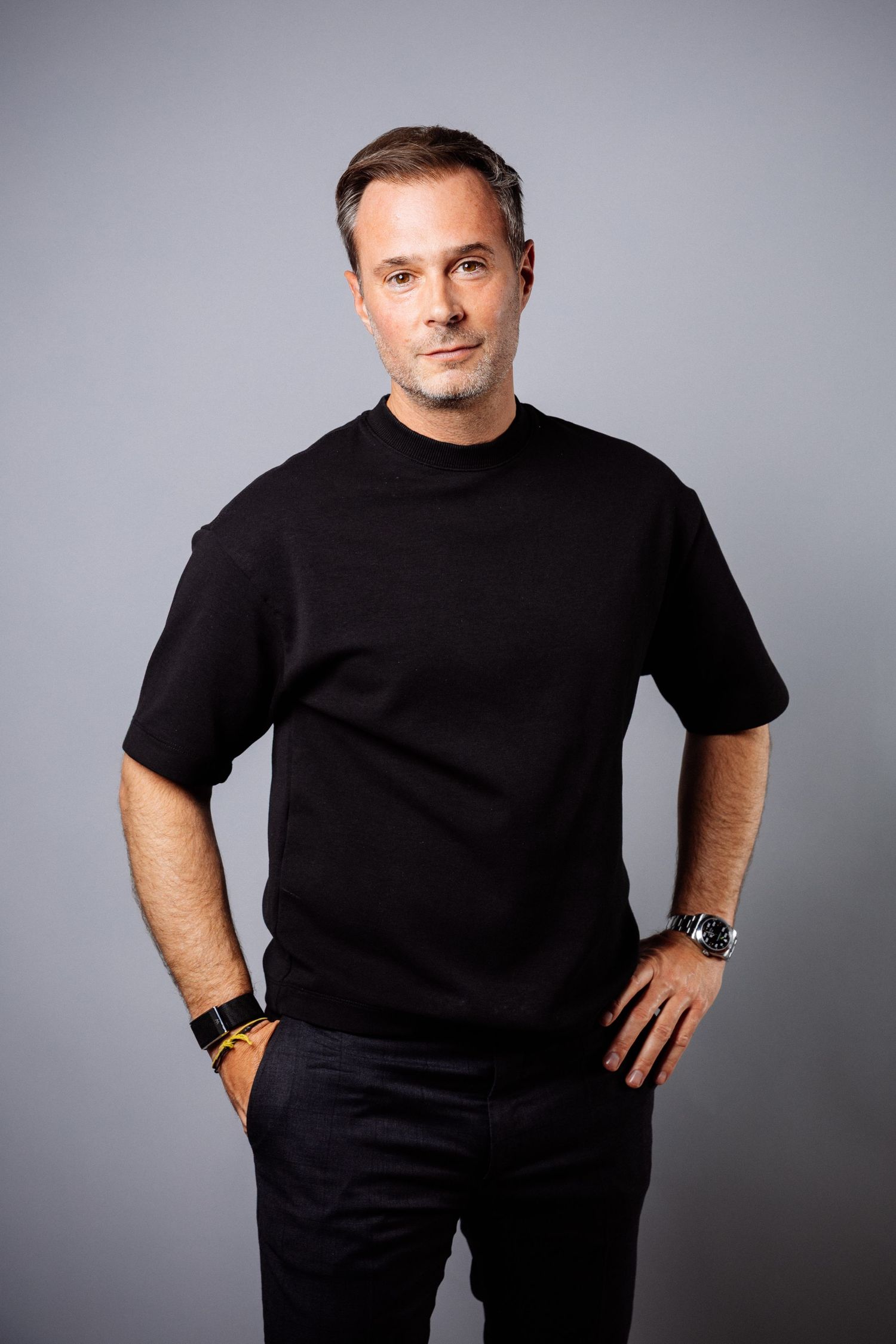 Black and white portrait of someone wearing a white button-up shirt with rolled sleeves in an outdoor setting.