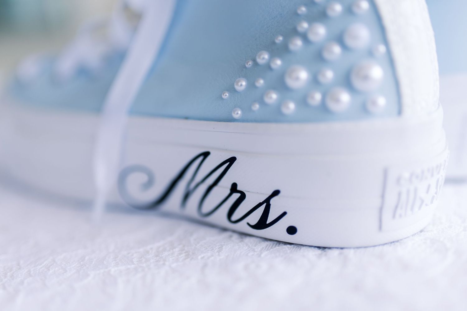 Close-up details of wedding dress embellishments with delicate pearl and crystal beading in soft focus.