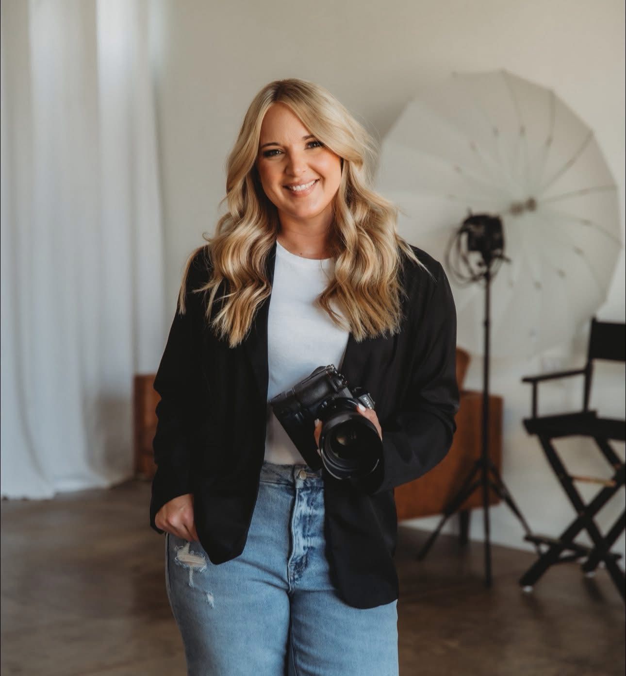 Professional photographer holding camera against grey background.