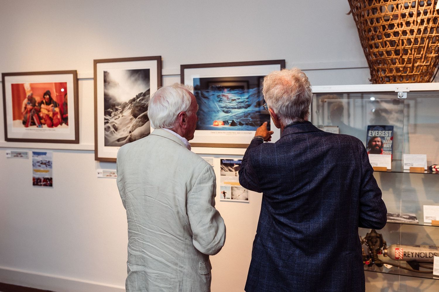 Gallery visitors explore a photography exhibition featuring framed artworks mounted on white walls.