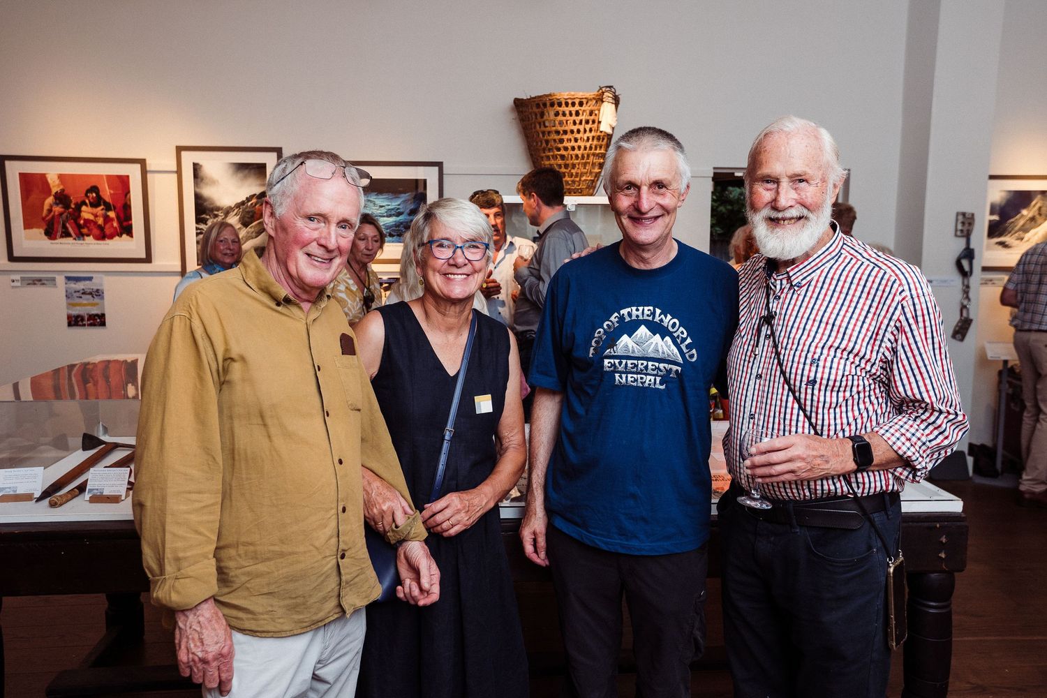 A group poses together at an art gallery or exhibition space with photographs displayed on the walls in the background.
