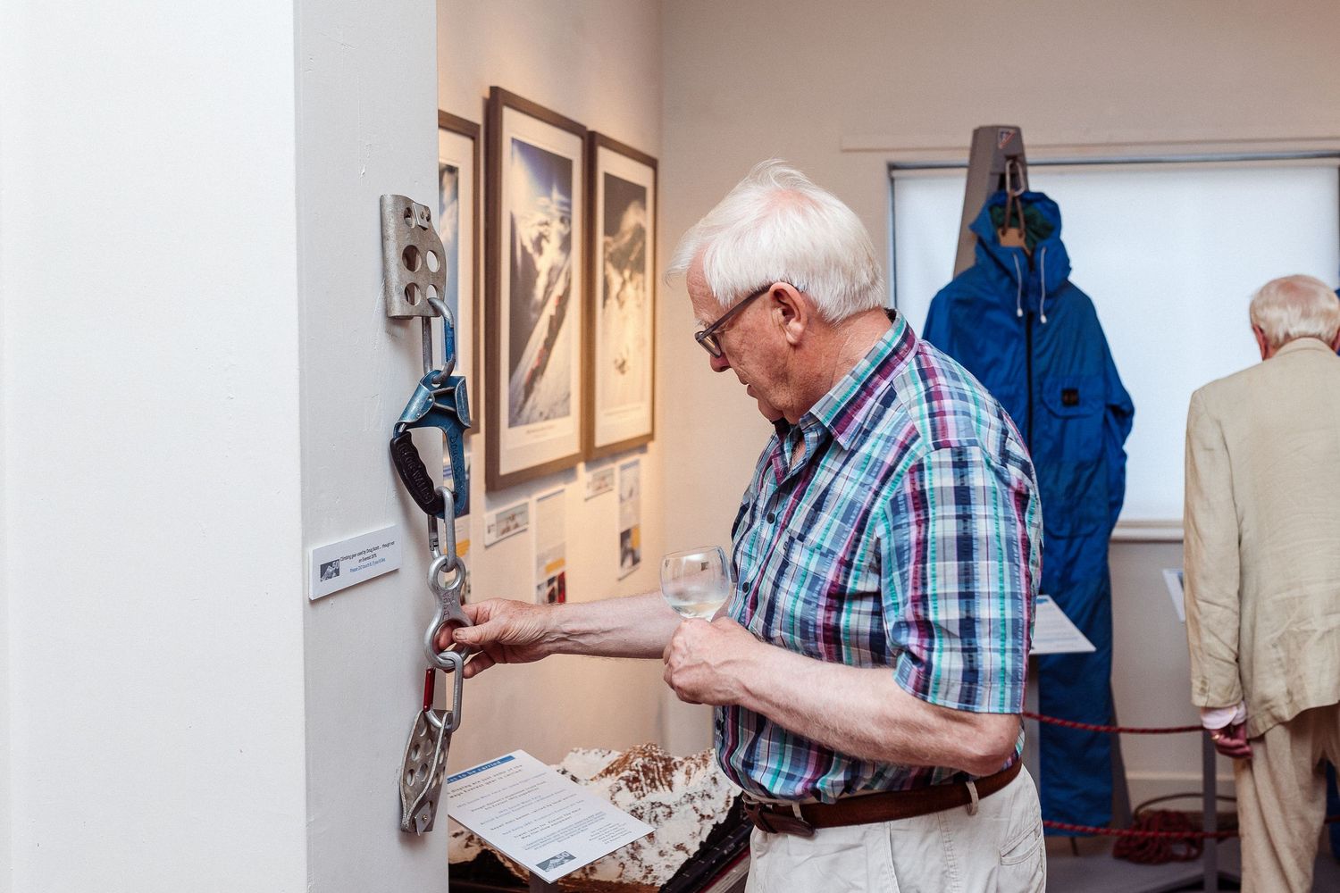 A person in a plaid shirt examines artwork during a gallery exhibition viewing.