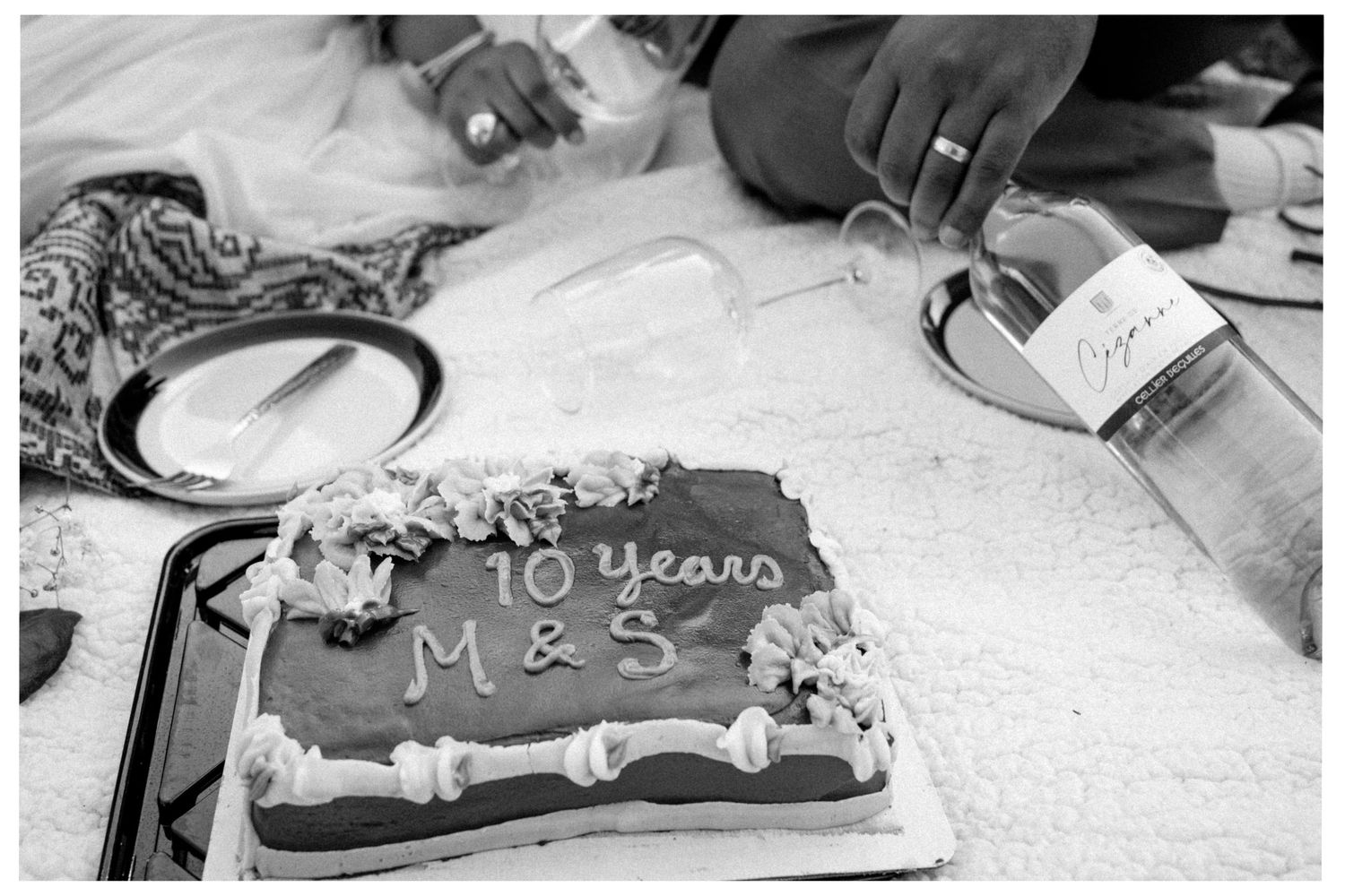 A black and white photograph shows a decorated chocolate cake marking a 10-year anniversary celebration with M&S written on top.