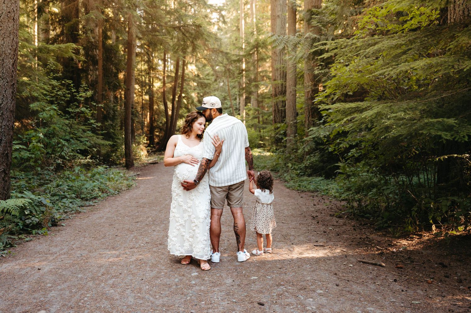 A group walks along a serene forest path surrounded by tall evergreen trees.