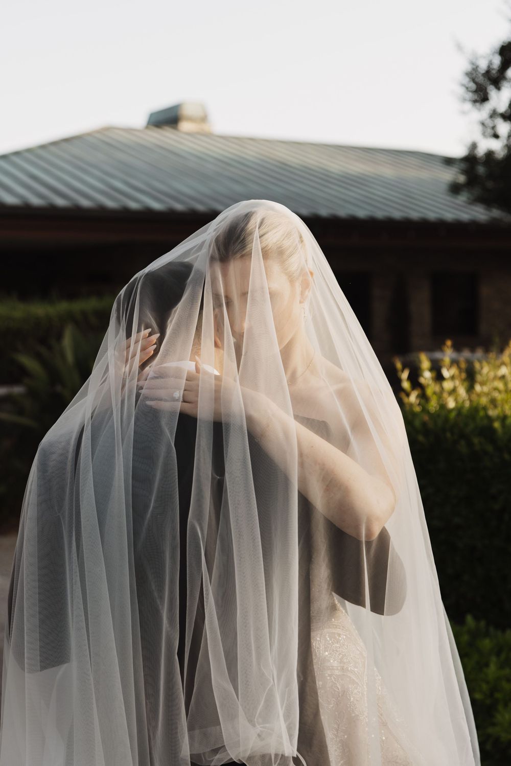 A delicate wedding veil blowing in the wind against a natural outdoor background.