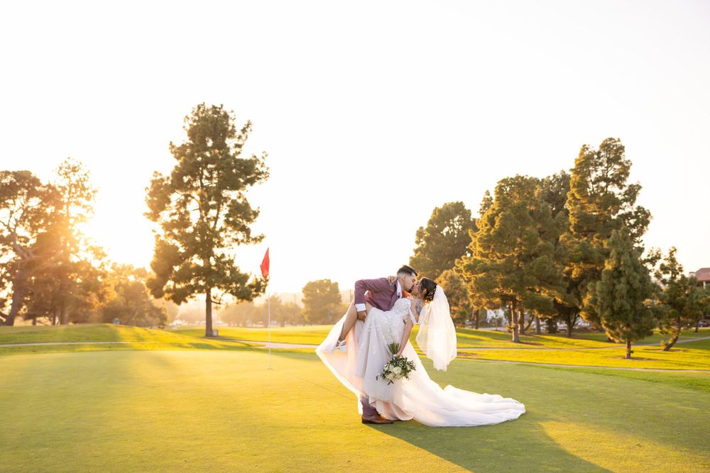 Dancing newlyweds silhouetted against setting sun on golf course.