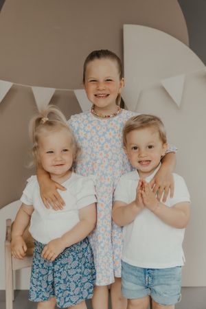 Group of young children in blue and white outfits posing together against neutral background.
