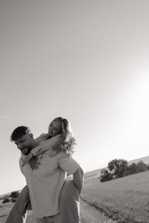 Joyful couple embracing and spinning in an open field during golden hour.