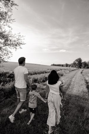 Black and white candid of family walking together through rural landscape.