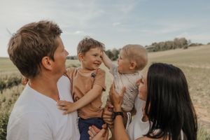 Family sharing joyful moments together in sunny outdoor field.