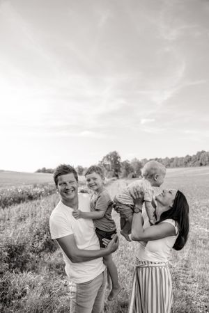 Family sharing joyful moments together in a sun-drenched field during an outdoor photo session.