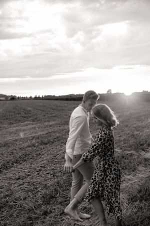 Candid moment of a couple dancing in a field during sunset.