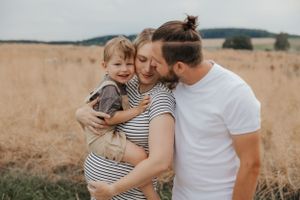 Happy family of three sharing affectionate moments together in an outdoor setting.