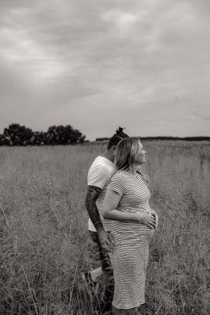 Expectant mother standing in a serene field during a maternity photo session.